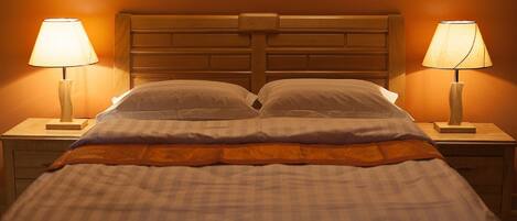 A double bed with a wooden headboard, two bedside tables with lamps, and a checkered bedspread.