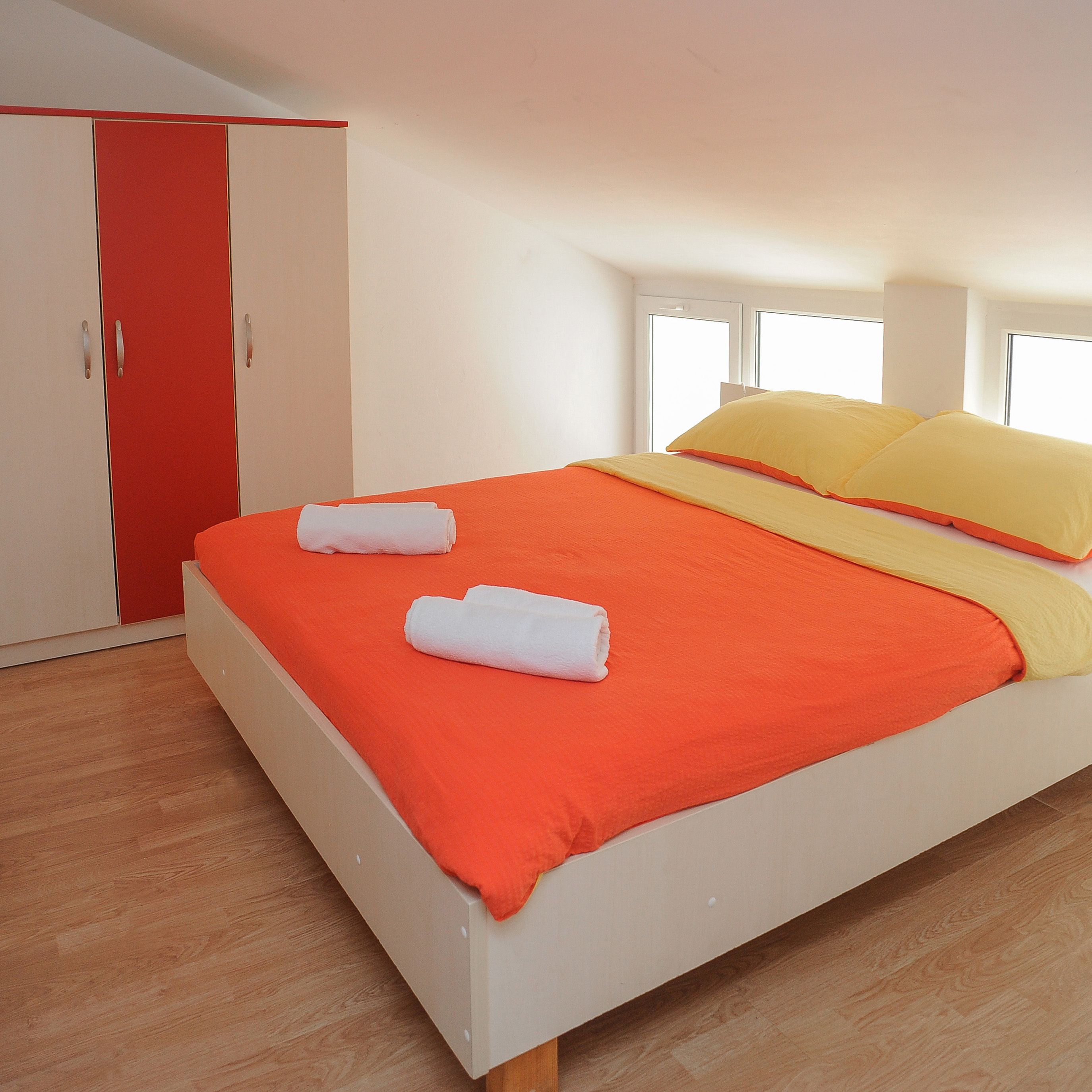 Ein Schlafzimmer mit einem Bett, einem roten Kleiderschrank und einem Fenster.