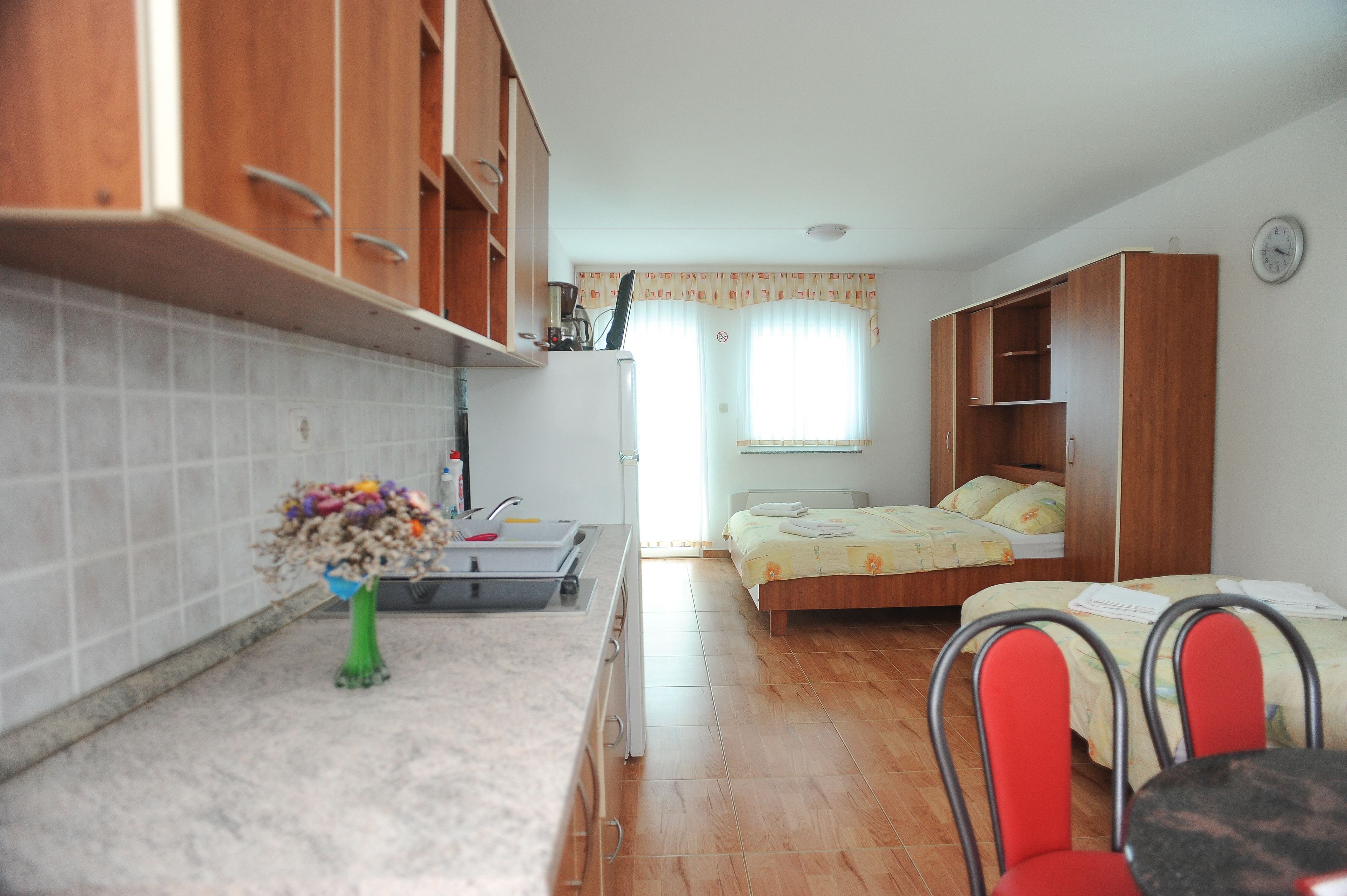A compact room with a kitchenette, a bed, and a dining area.