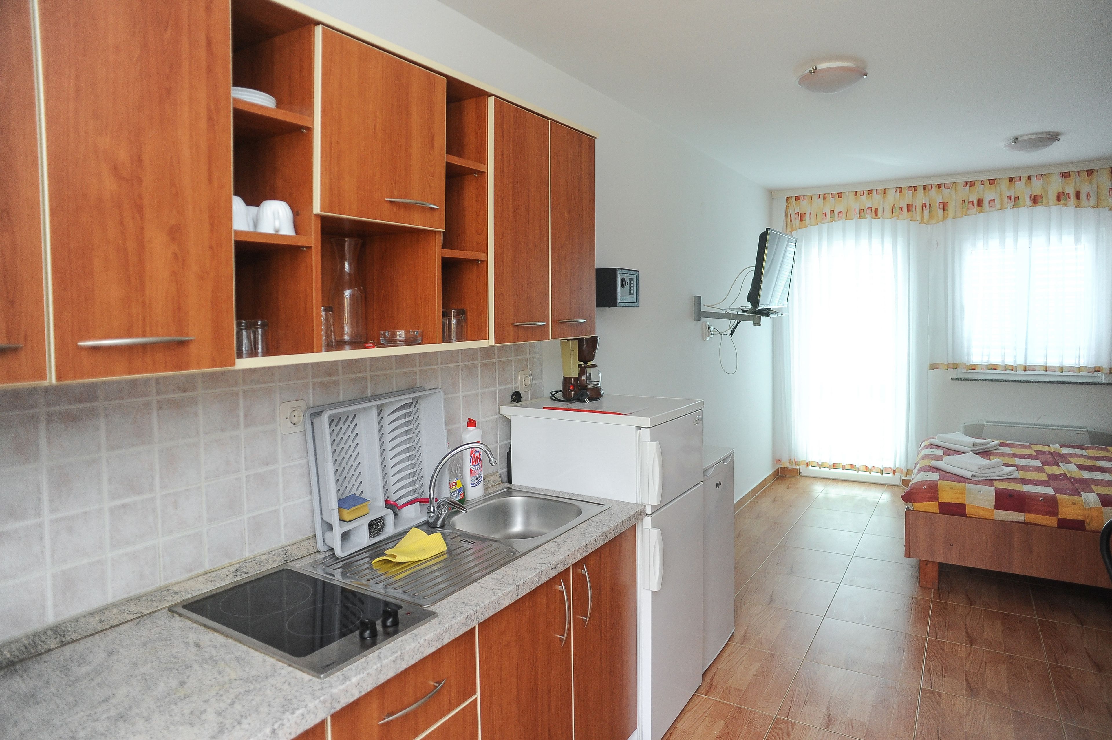 A compact kitchen with wooden cabinets, a built-in stove, and a small refrigerator.