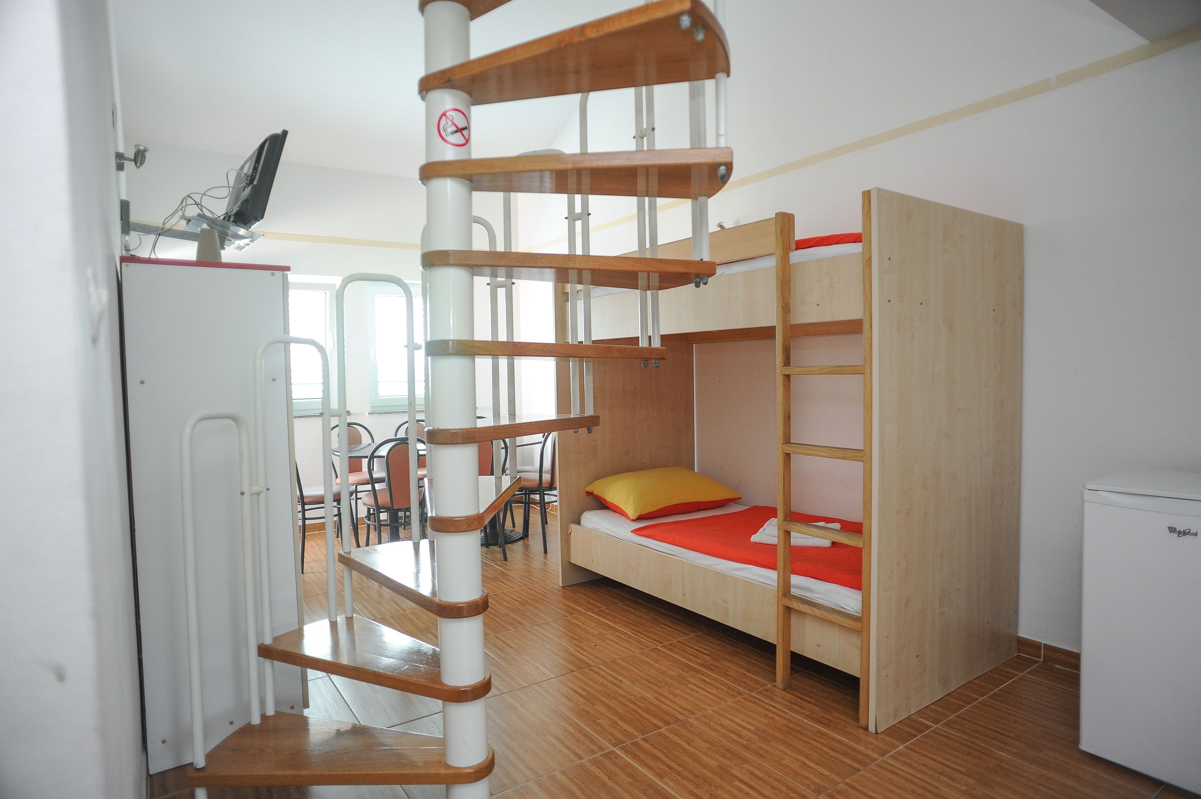 A compact room with a bunk bed, a desk with a computer, and a chair.