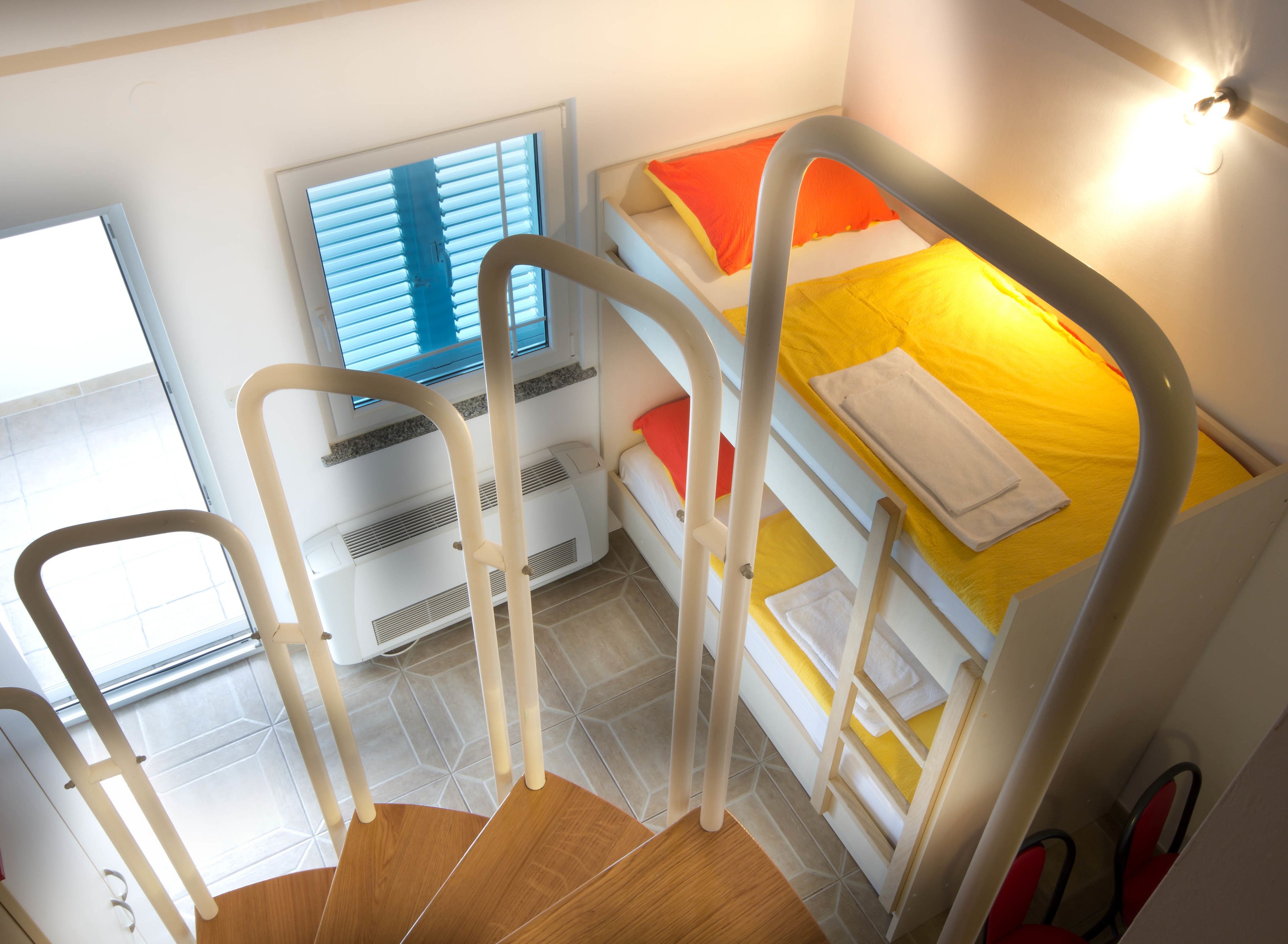 Una habitación con literas, una ventana con persianas, un calentador y una silla.