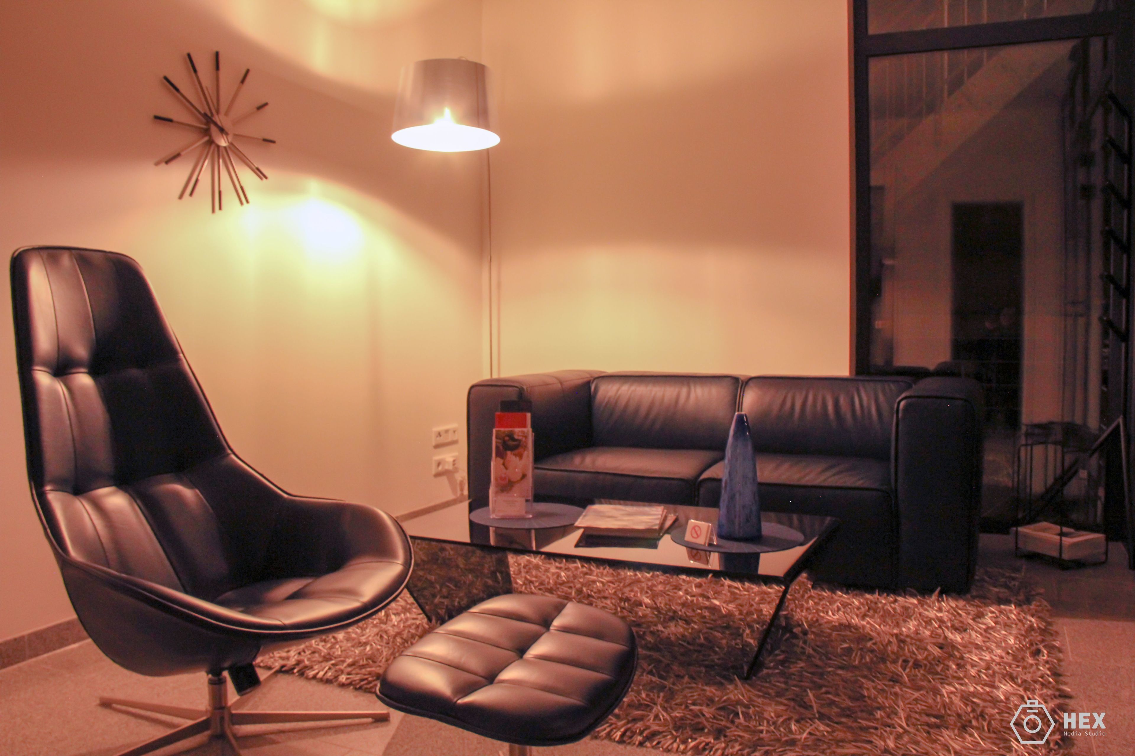 A modern living room with a black leather chair, a black leather sofa, and a coffee table.