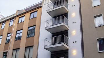 Un edificio de varios pisos con balcones, una librería en la planta baja y un coche estacionado.