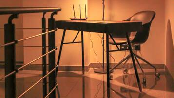 Ein Zimmer mit Glastisch, einem Stuhl, einer Lampe und einem Geländer.