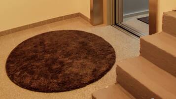 Una zona alfombrada con un tapete circular, un conjunto de escalones color beige y una puerta que da a una habitación.