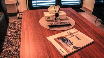 Una mesa de madera con un control remoto, una caja de pañuelos y una guía de bienvenida.