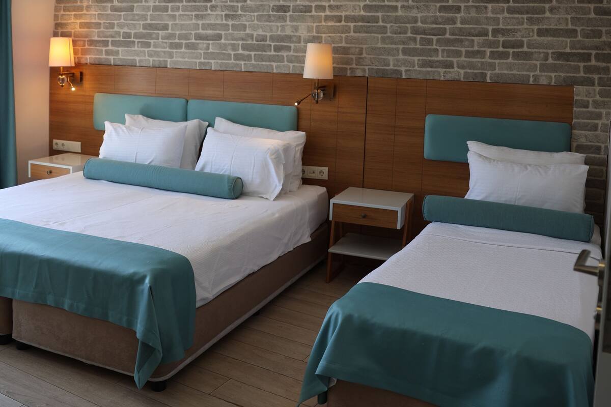 A hotel room with two beds, a brick wall, and a wooden headboard.