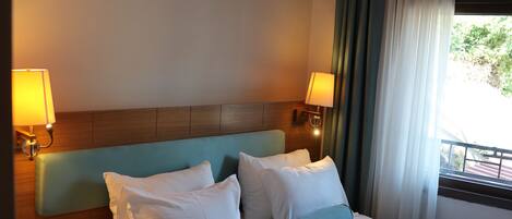A hotel room with a bed, bedside tables, lamps, and a window with curtains.