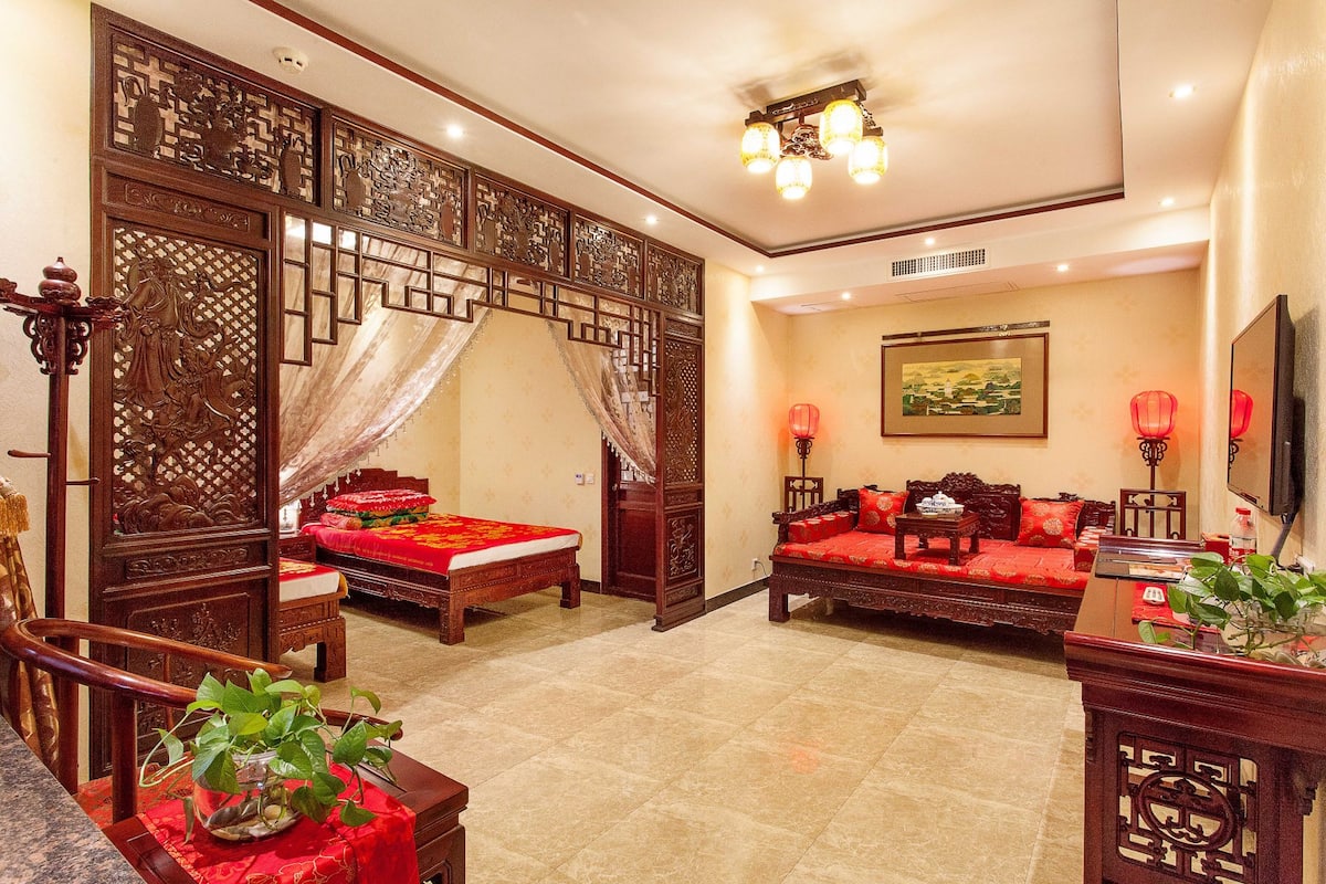 A traditional Chinese-style room with a wooden bed, a sofa, and a decorative screen.