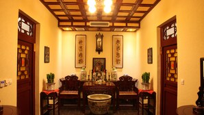 A traditional room with a large central table, two chairs, a decorative vase, and framed calligraphy on the walls. - Cheng Shi Ge Hotel (Jinzhong)