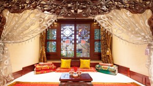 A traditional room with a bed, pillows, and a table with teapots. - Cheng Shi Ge Hotel (Jinzhong)