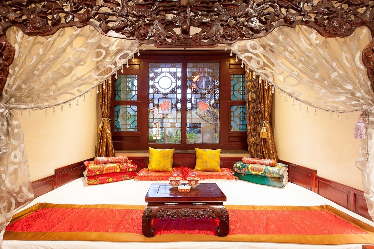 A traditional room with a bed, pillows, and a table with teapots.