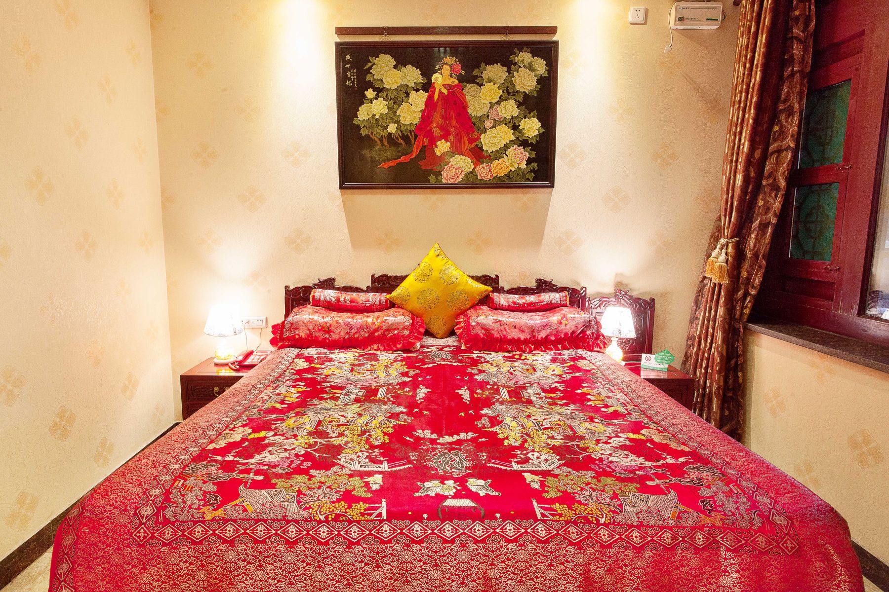 A hotel room with a large bed, a painting on the wall, and a window with curtains.
