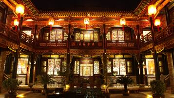 Un bâtiment traditionnel chinois, doté d’une architecture richement décorée, de grandes fenêtres et de plantes en pot.