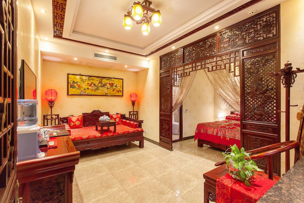 A traditional Chinese-style room with a sofa set, a bed, and a decorative screen.