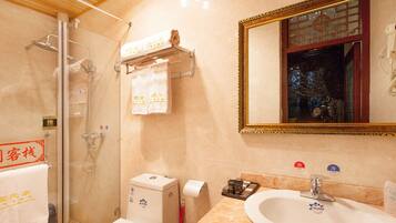 A bathroom with a glass shower, a toilet, a sink, and a mirror with a decorative frame.