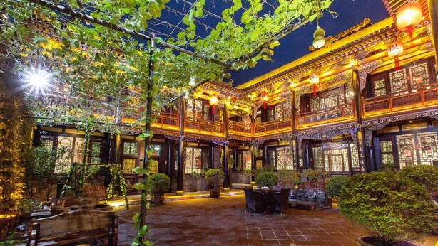 A traditional courtyard with tiled flooring, wooden furniture, and potted plants. - Cheng Shi Ge Hotel (Jinzhong)