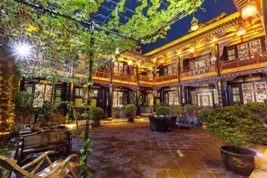 Un patio tradicional con suelo de baldosas, muebles de madera y plantas en macetas.