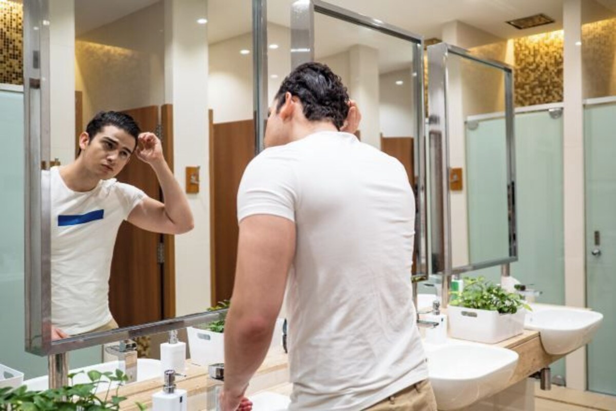 A modern bathroom with a large mirror, two sinks, and a wooden vanity.