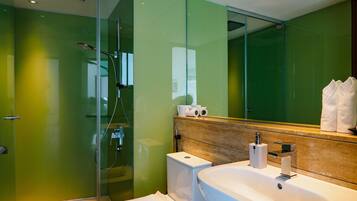 A modern bathroom with a glass shower enclosure, a white toilet, and a large sink with a wooden countertop.