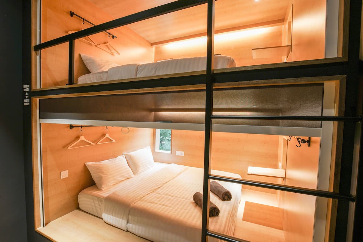 Habitación con literas, ventana, paredes de madera y lámpara colgante.