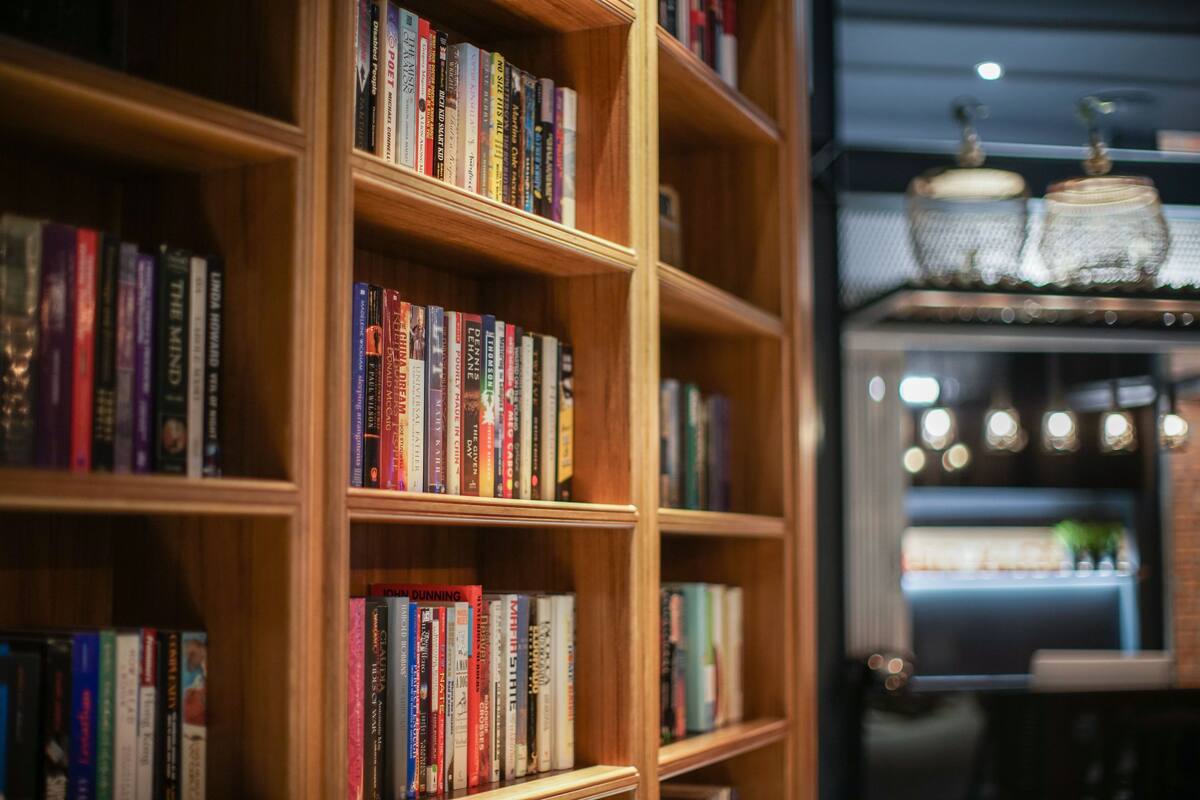 Una estantería llena de libros, un frasco de vidrio decorativo y una planta pequeña en un estante.