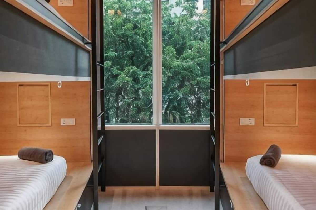 Una habitación con dos camas, una ventana y vista a árboles.