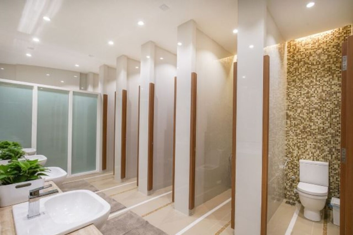 A modern bathroom with a large mirror, a white sink, and a shower area.