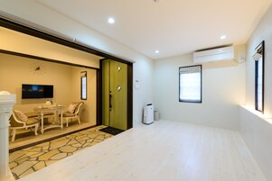 Habitación de hotel con zona de comedor, televisión, aire acondicionado y ventana.