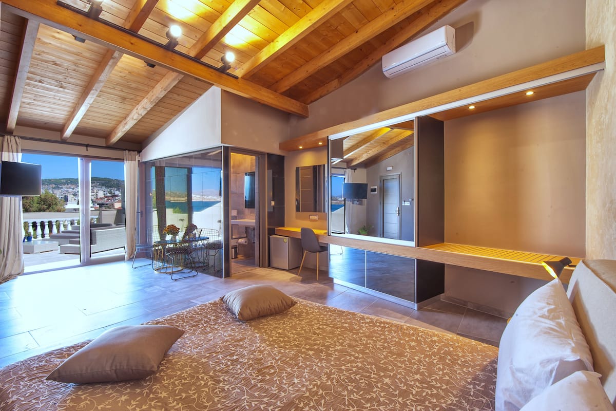 Un dormitorio moderno con una cama grande, un escritorio y vistas de la ciudad a través de amplios ventanales.