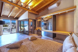 Un dormitorio moderno con una cama grande, un escritorio y vistas de la ciudad a través de amplios ventanales.