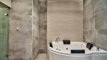 Une salle de bain moderne avec une baignoire sur pieds, des murs carrelés et une douche à parois de verre.
