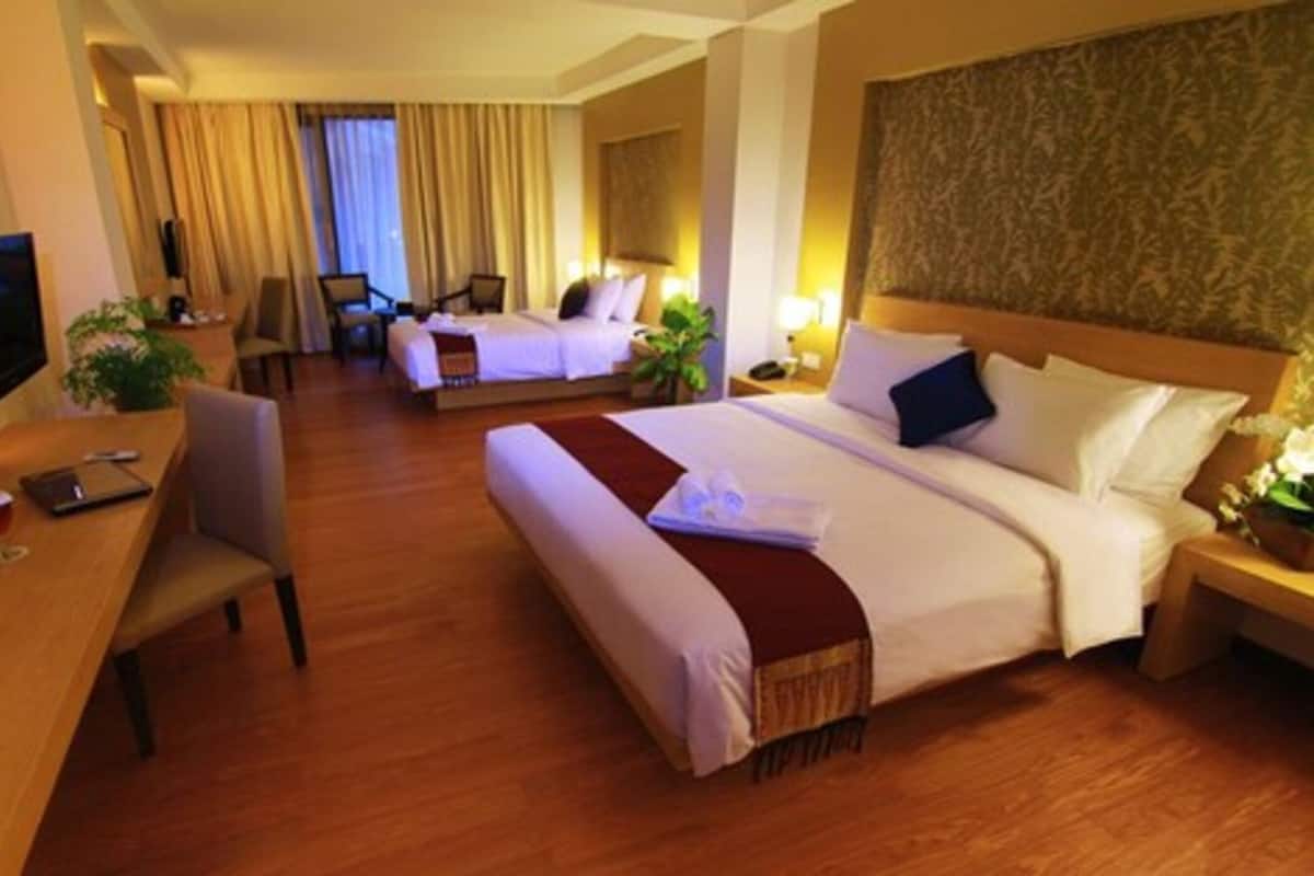 A hotel room with two beds, a desk, a chair, a television, and a large window with curtains.
