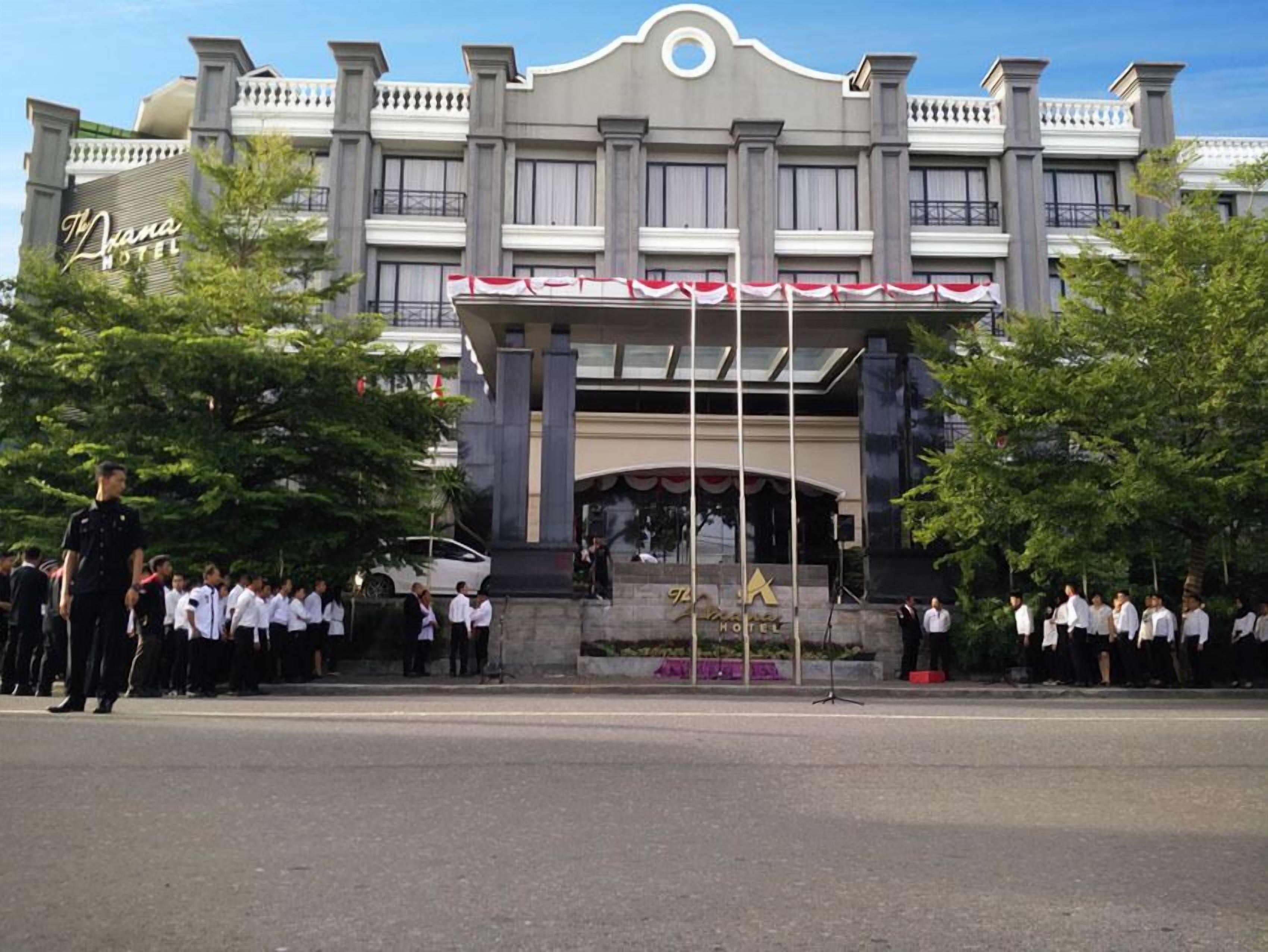 A hotel with a grand entrance, a balcony, and a flagpole.