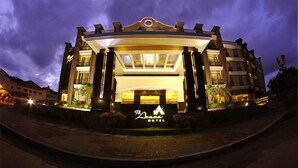 A hotel with a prominent entrance, a large sign with the hotel's name, and a well-lit facade. - The Axana Hotel (Padang)