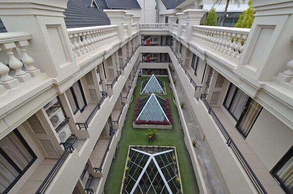 A multi-level building with a central courtyard featuring geometric glass structures and green landscaping.