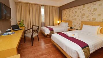 A hotel room with two beds, a desk, a chair, a TV, and a window with curtains.