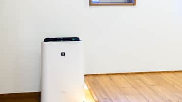 A white air conditioning unit in a room with wooden flooring and a white wall.