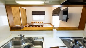 Una kitchenette compacta con lavamanos, estufa y comedor con mesa y sillas.