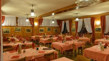 Ein Restaurant mit mehreren gedeckten Tischen, Holzvertäfelung an den Wänden und hängenden Leuchten.