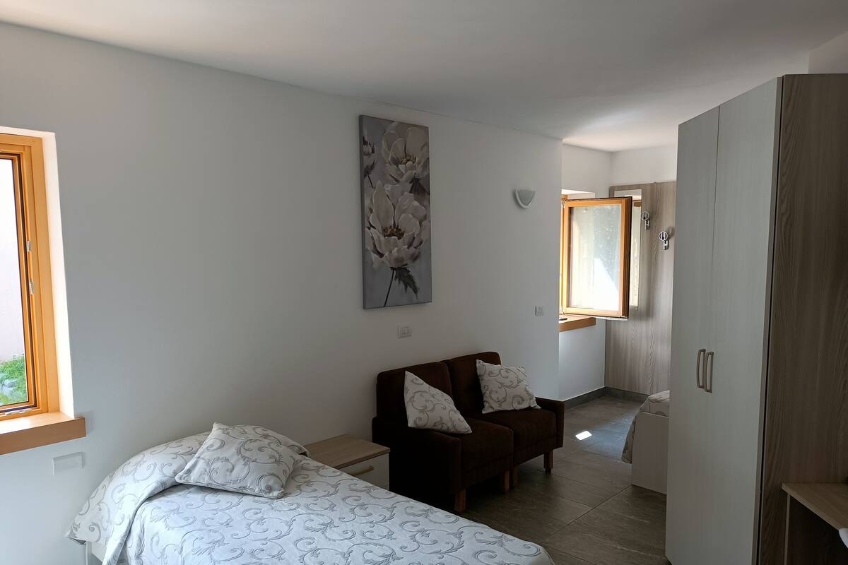 Ein Schlafzimmer mit einem Bett, einem Sessel, einem Kleiderschrank und einem Bild an der Wand.