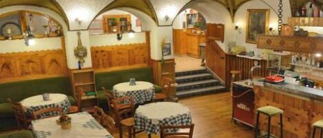 Un restaurante acogedor con cabinas de madera, mesas redondas y una zona de bar.