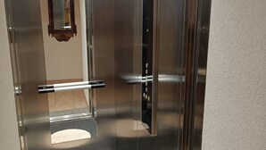 En elevator med metalvægge, et spejl og et kontrolpanel.