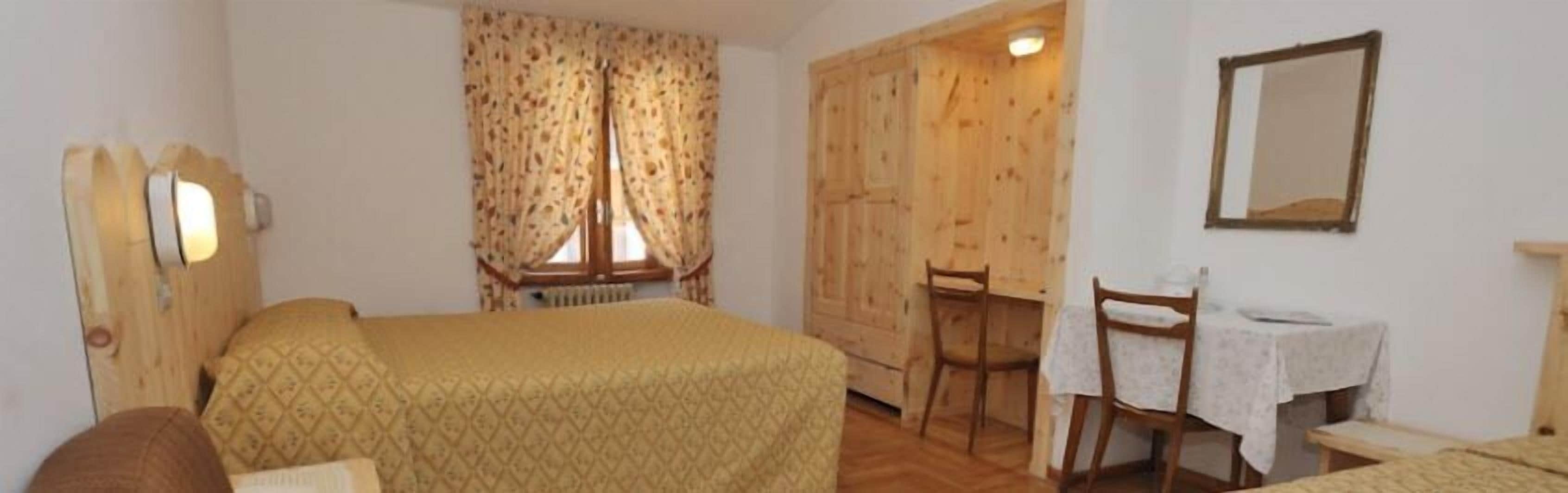 A room with a bed, a desk, a chair, a mirror, and a wardrobe.