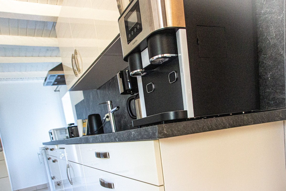 Une cuisine moderne équipée d’une machine à café, d’un four à micro-ondes et d’un grille-pain.