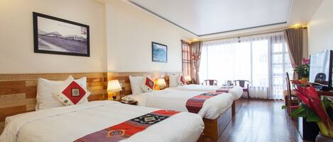 A hotel room with two beds, a desk, a chair, a TV, and a window with curtains.
