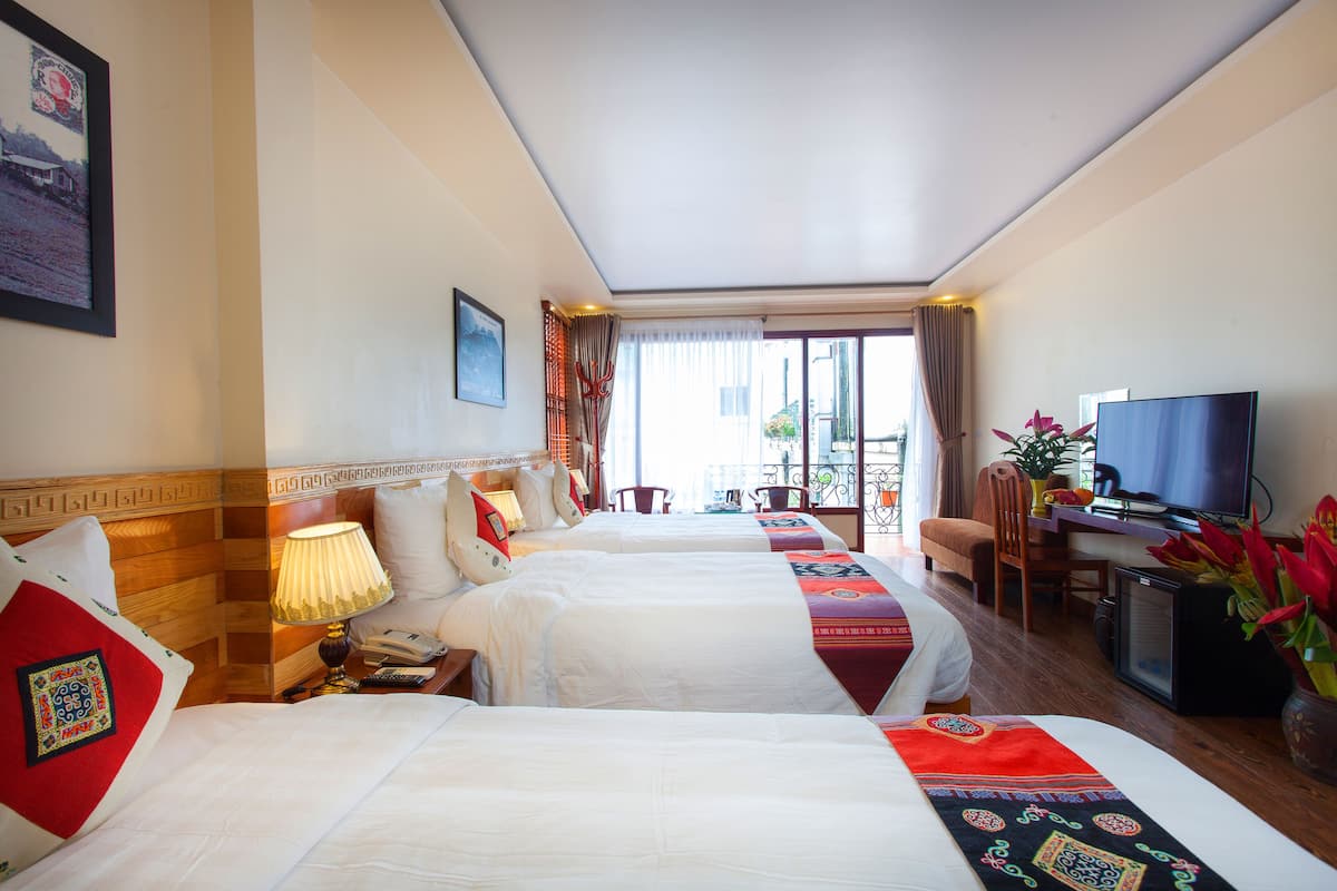 Habitación de hotel con dos camas, un escritorio con televisor y una ventana con cortinas.