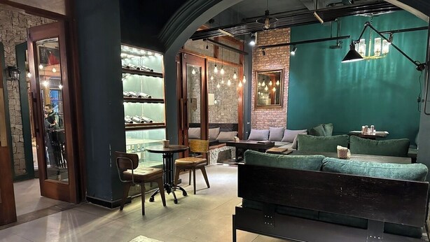A cozy lounge area with a sofa, chairs, and a coffee table. There is a glass display case in the background. - Sapa Centre Hotel (Sa Pa)