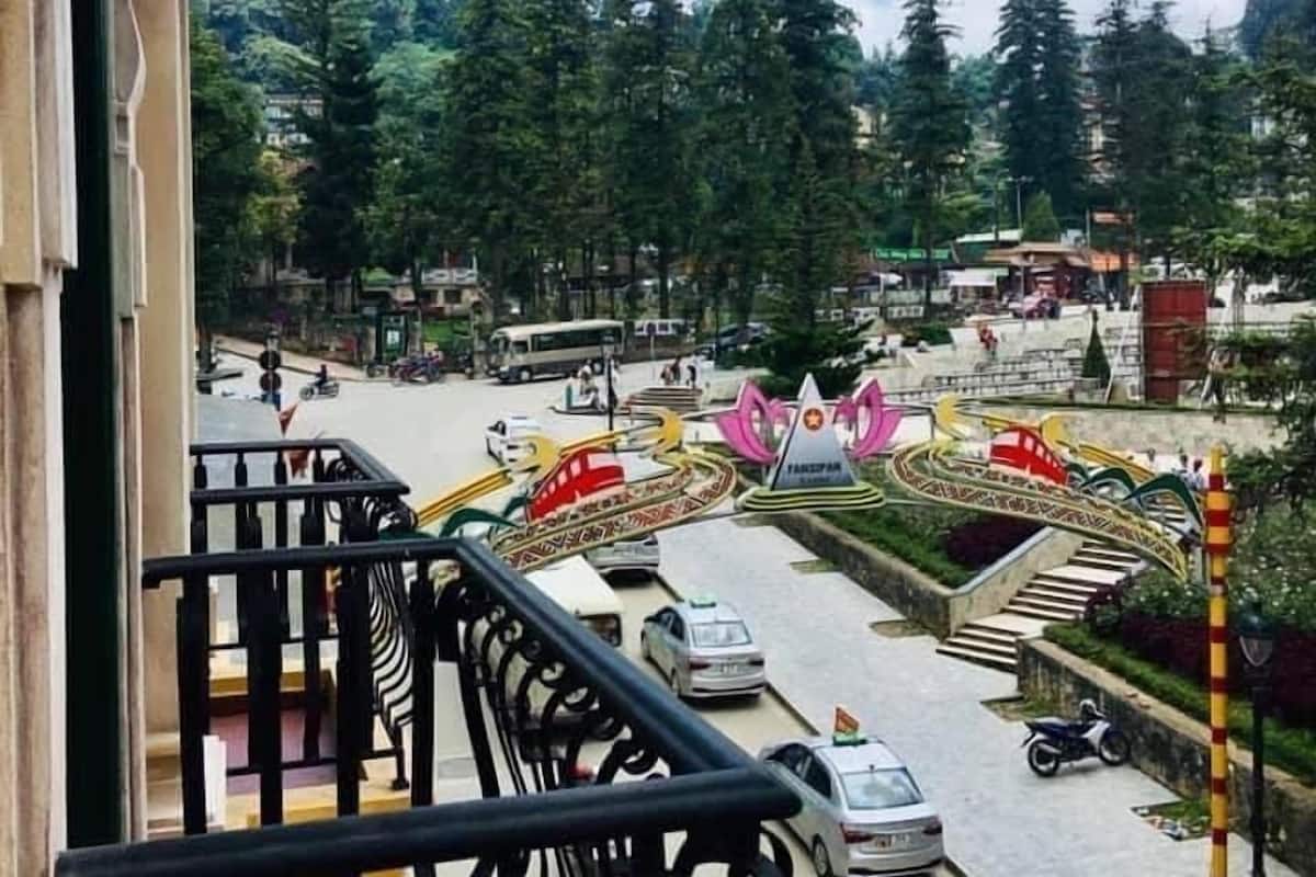 Vista desde un balcón sobre una calle con un puente peatonal colorido y coches estacionados.